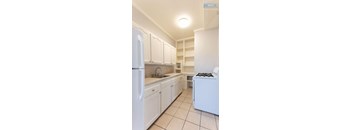 A kitchen with white cabinets and a white refrigerator.