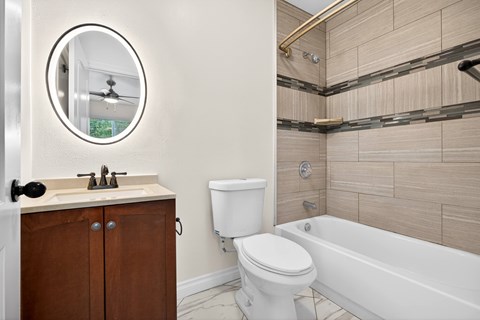 A bathroom with a white toilet and a round mirror.