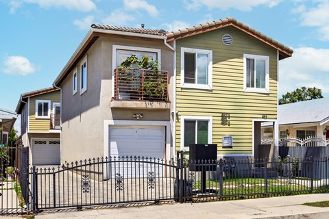 A yellow house with a black gate in front.
