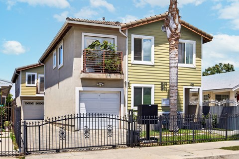 A yellow house with a black gate in front.