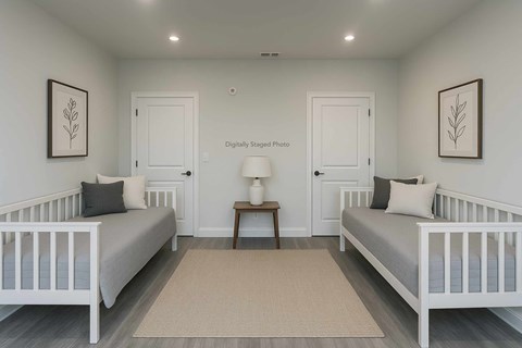 A white nursery with two cribs and a small table with a lamp.