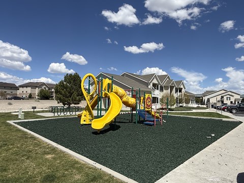 A playground with a yellow slide and a red and yellow sign.