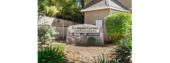 A sign for Campus Corner Apartments is displayed in front of a building.