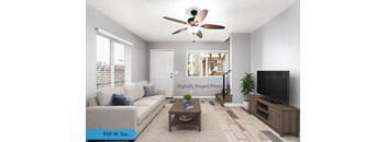 A living room with a couch, a coffee table, a ceiling fan, and a television.