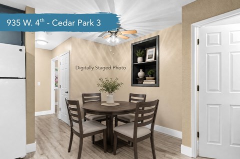 A dining room with a table set for two and a framed picture on the wall.