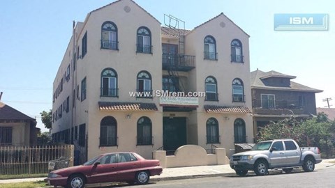 A red car is parked in front of a two-story building.
