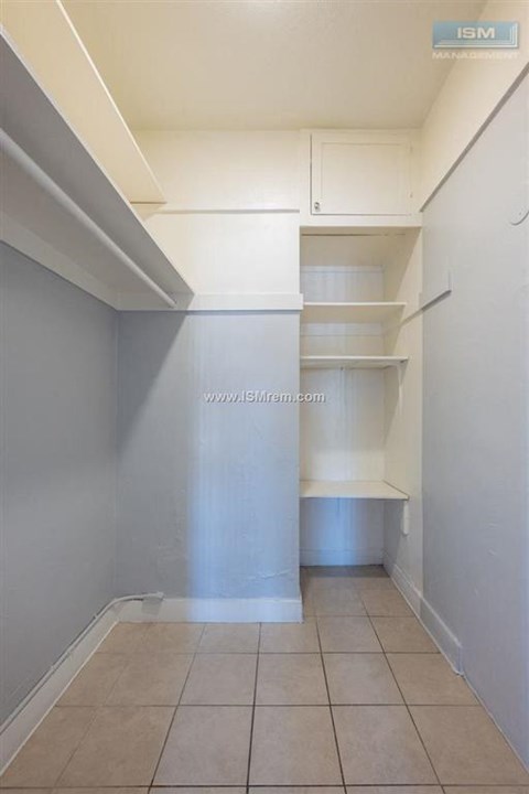 A long hallway with a white wall and tile floor.