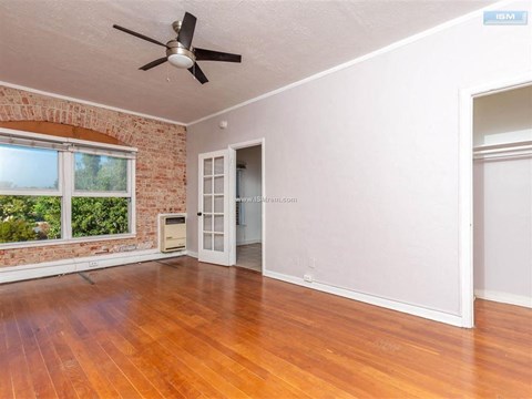 A room with a ceiling fan and a brick wall.
