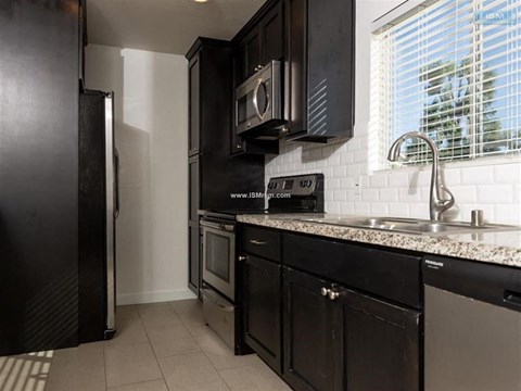 A kitchen with black cabinets and a white tiled backsplash.