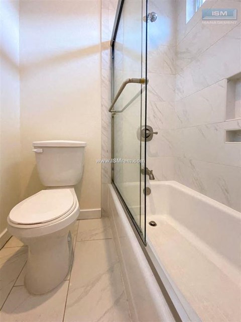 A white toilet sits next to a glass shower door in a bathroom.
