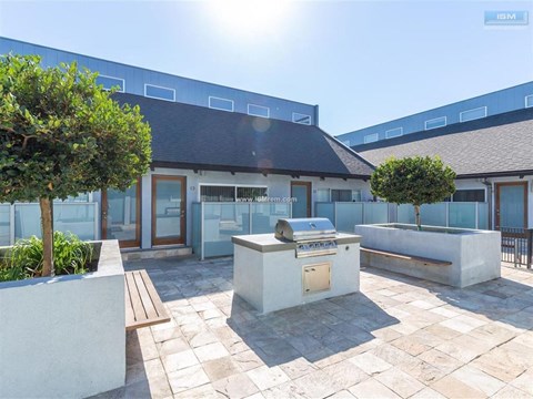 A sunny day at a modern building with a BBQ grill in the courtyard.