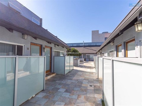 A sunny day at the courtyard of a building with glass walls and tiled floors.