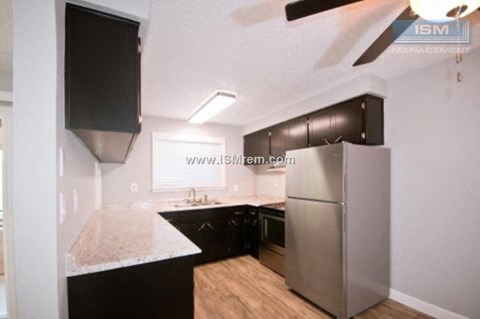 A kitchen with a black counter top and a stainless steel refrigerator.