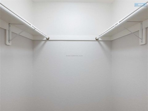 A white wall with a shelf and pipes.