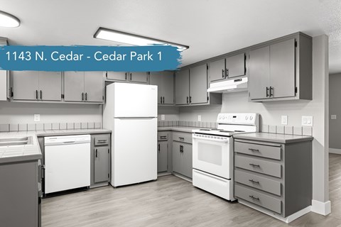 L shaped kitchen with gray cabinetry and white appliances at Cedar Park Apartments, Chico