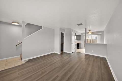 A spacious room with wooden flooring and white walls.