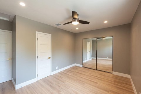 A room with a ceiling fan and mirrored door.