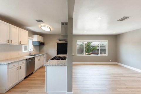 A kitchen with white cabinets and a black fridge.
