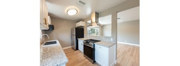 A kitchen with a granite countertop and a black refrigerator.
