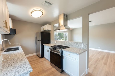 A kitchen with a granite countertop and a black refrigerator.