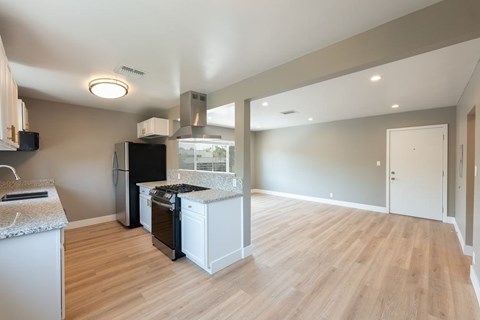 A kitchen with a black fridge and white cabinets.