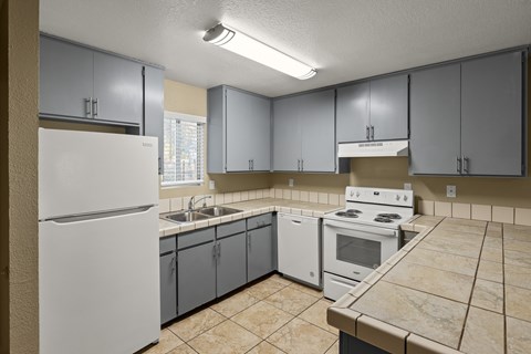 A kitchen with a white refrigerator, white oven, and grey cabinets.