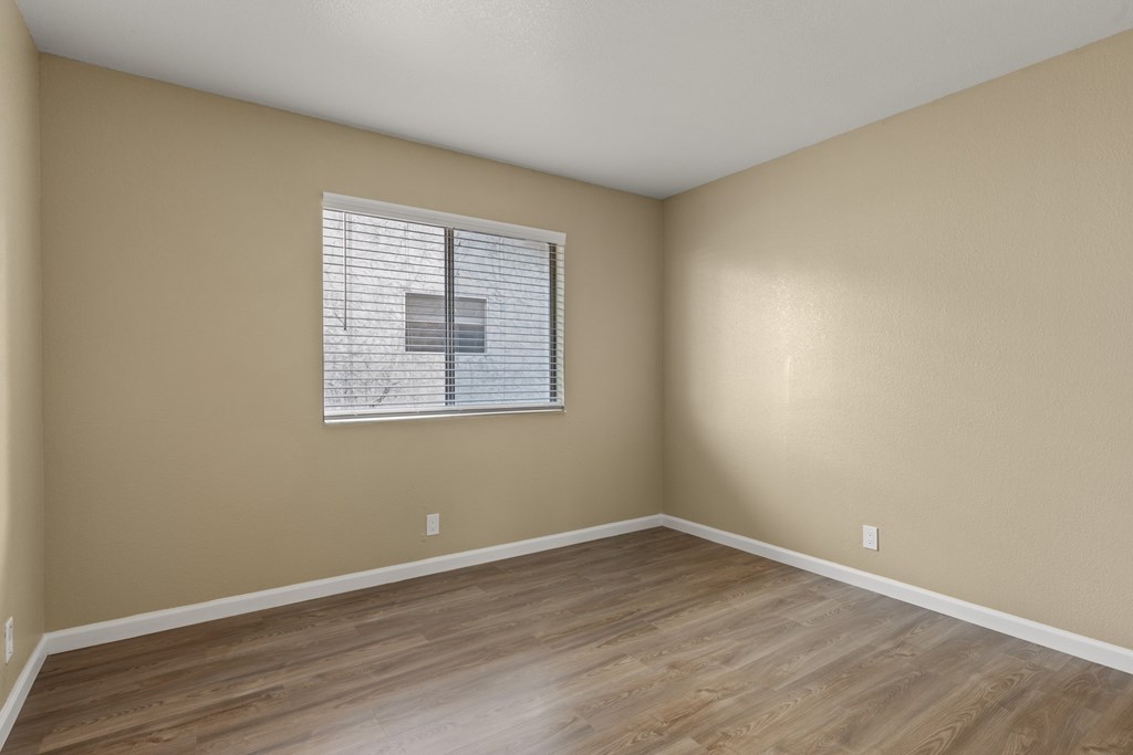 A room with wooden flooring and a window with blinds. at Cedar Park Apartments, Chico, California