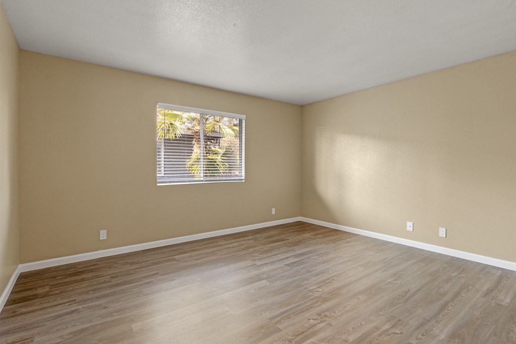 A room with wooden flooring and a window with blinds. at Cedar Park Apartments, Chico
