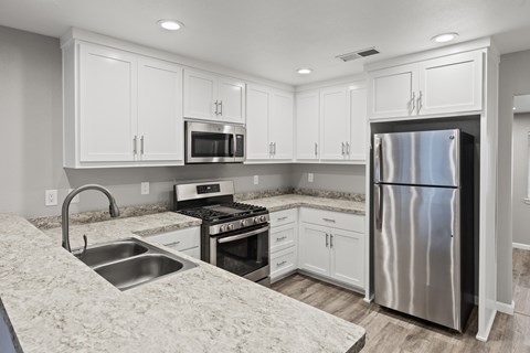 A kitchen with white cabinets and a stainless steel refrigerator.