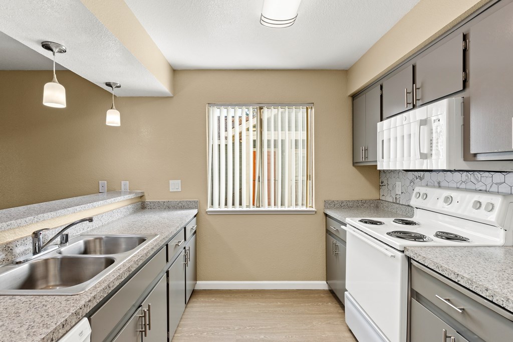 A kitchen with a stove, sink, and cabinets. A kitchen with a stove, sink, and cabinets.at Redwood Cove Apartments, Chico, CA