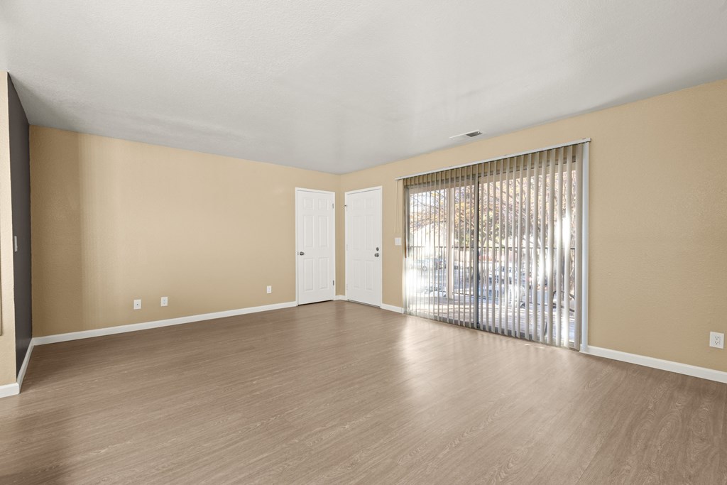 Empty room with wooden floors and a sliding glass door.at Redwood Cove Apartments, Chico California  