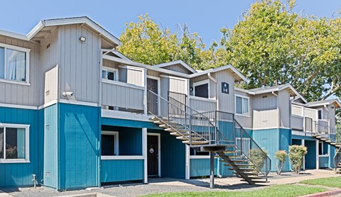 a row of blue condos with stairs and trees at Creekview Homes, California, 95928