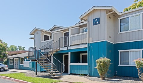 Apartment complex with a blue and white building and a car parked in front.
