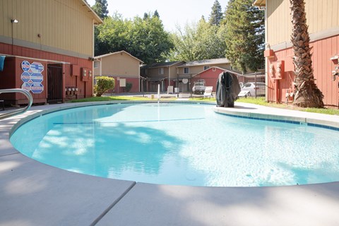 Outdoor swimming pool with surrounding buildings at Pomona Townhomes Apartments, Chico