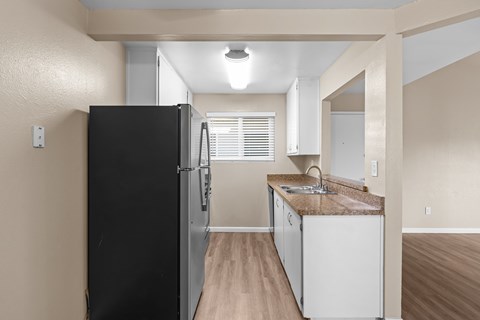 A kitchen with a black refrigerator and white cabinets.