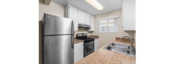 A kitchen with a stainless steel refrigerator, stove, and sink.
