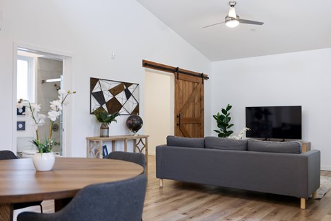 A living room with a grey couch, a wooden table, and a television.