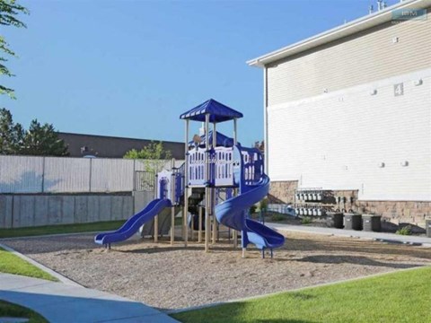A playground with a blue slide and a wooden structure.