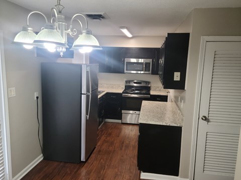 A kitchen with black appliances and a white door.