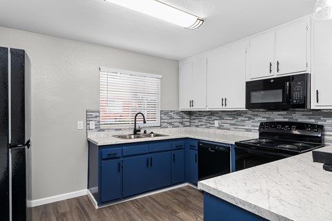 A kitchen with blue cabinets and a black refrigerator.