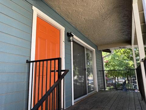 A blue house with a red door and a black railing.