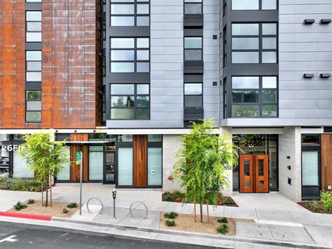 A modern building with a red brick facade and a grey facade with windows.
