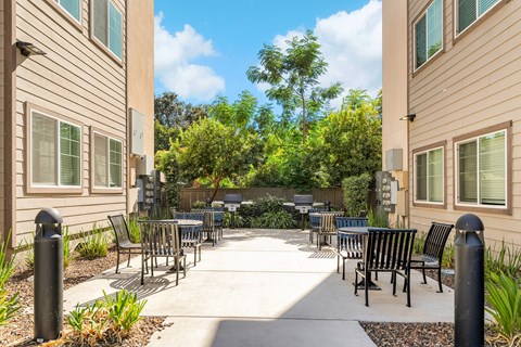 A patio area with chairs and tables surrounded by buildings.