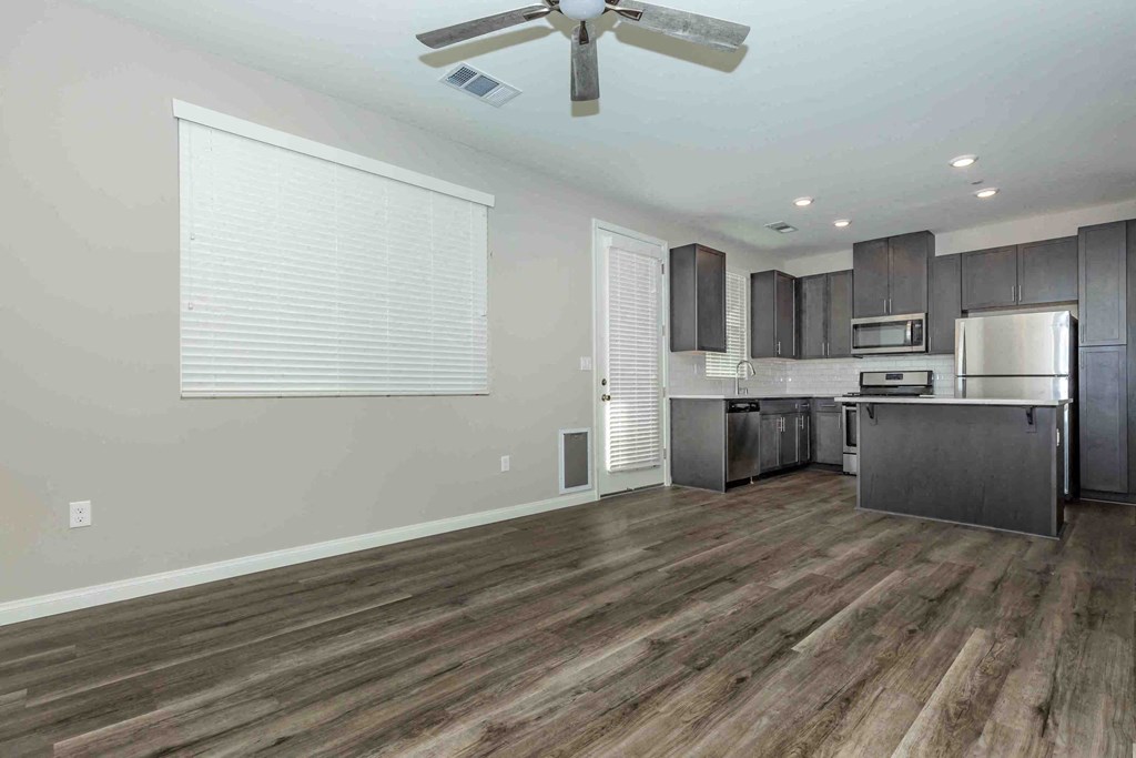 an empty kitchen and living room with a ceiling fan