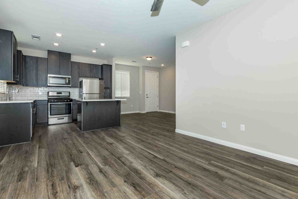 a kitchen and living room with wooden floors and black cabinets