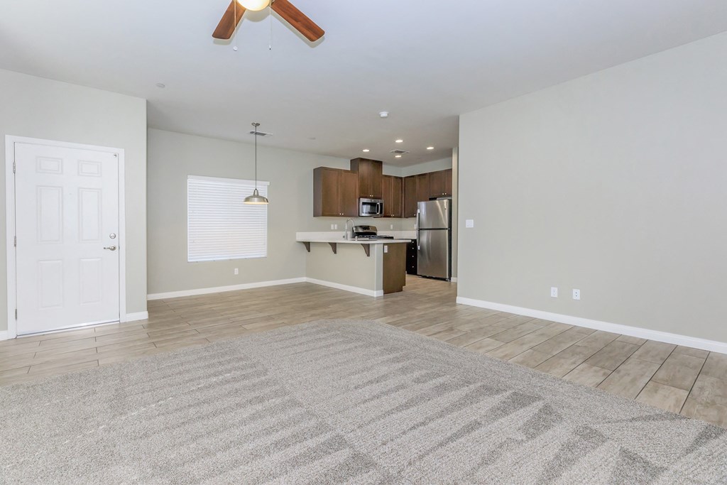 an empty living room and kitchen with a ceiling fan