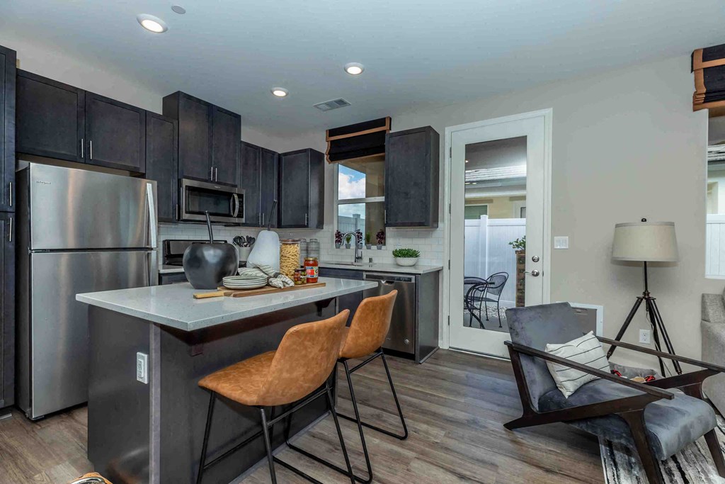 a kitchen with stainless steel appliances and a counter with two chairs