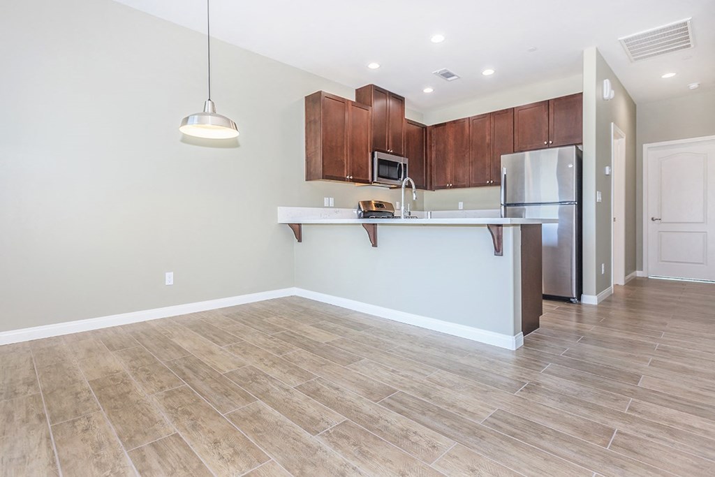 an empty kitchen and living room with a stainless steel refrigerator