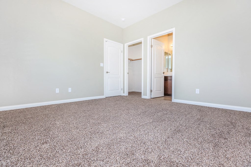 an empty living room with carpeting and a door to a bathroom