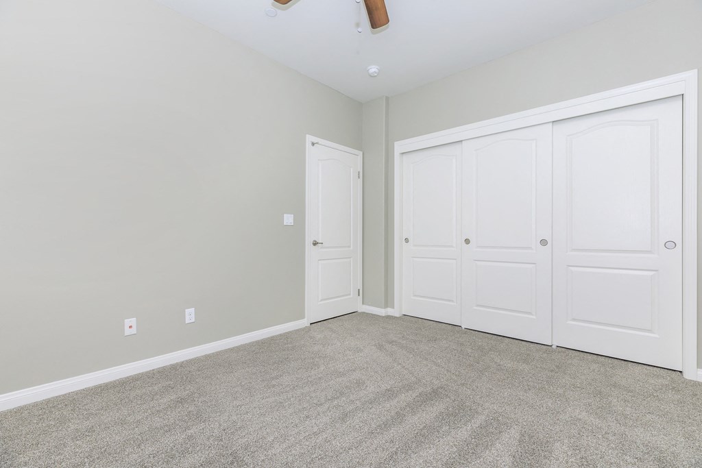an empty bedroom with two closets and a carpeted floor